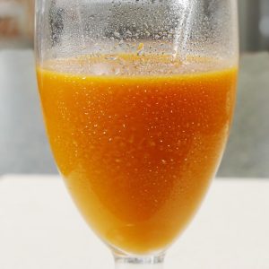 Fresh Pressed Carrot Juice in Stemmed Juice Glass with Straw on White Formica Countertop Food Picture