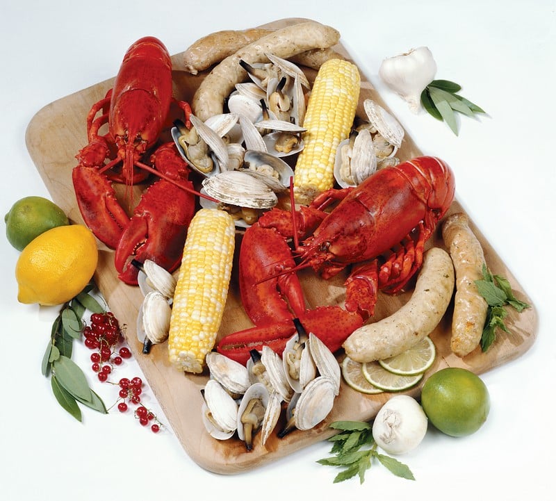 Clambake with corn on the cob and garnish on a wooden board Food Picture