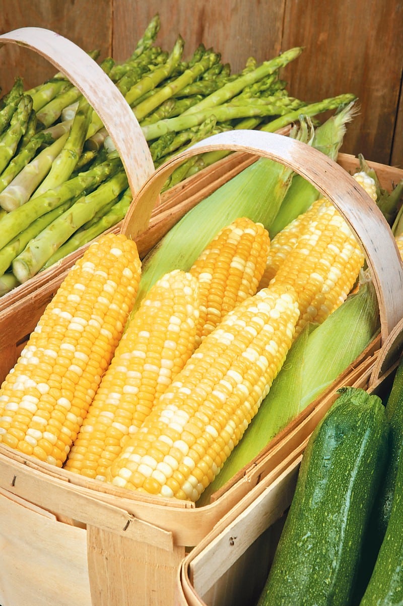 Corn on the cob in a wooden basket with asparagus and zucchini on either side Food Picture