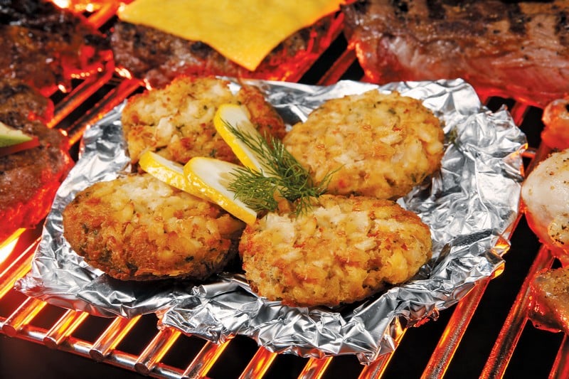 Crab Cakes on Foil on Grill with Lemon and Garnish Food Picture