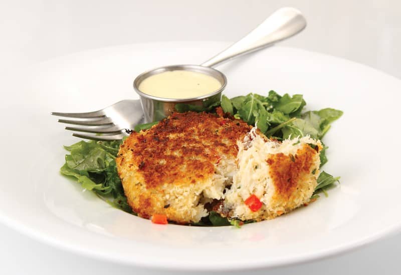 Crab Cake over Greens with Sauce and Fork in White Dish Food Picture