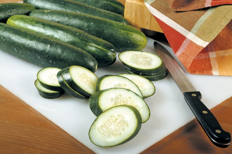 Whole and Sliced Cucumbers on Board Food Picture