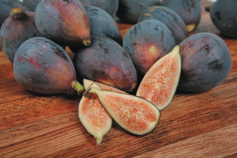 Whole and Quartered Figs on Wooden Surface Food Picture