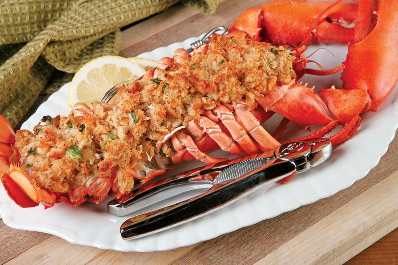 Baked stuffed lobster with tool on white plate over wooden surface Food Picture