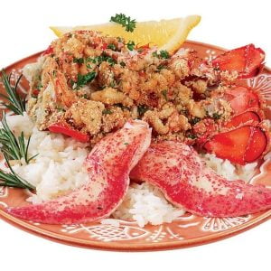 Baked stuffed lobster over rice with garnish on orange and white plate Food Picture