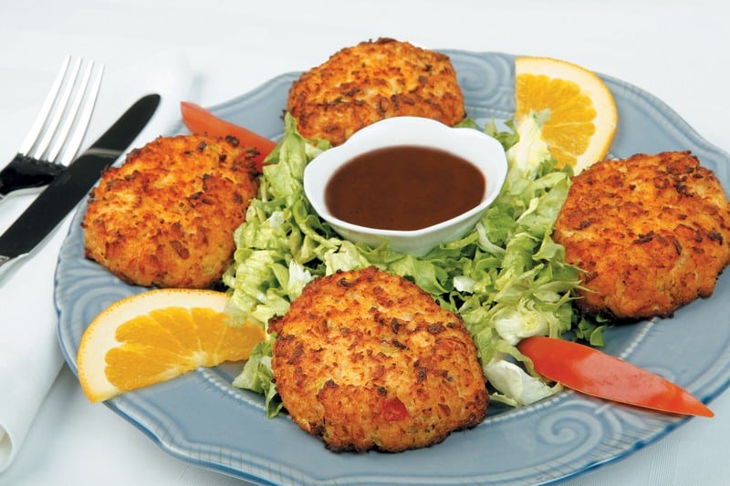 Lobster cakes with garnish and dipping sauce on blue plate Food Picture