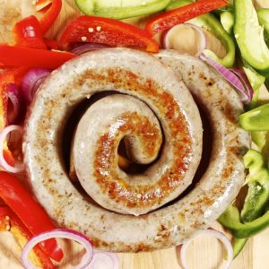 Freshly Fried Loop Sausage on a bed of Fresh Bell Peppers and Onions on Pine Tabletop Food Picture