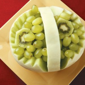 A Melon Boat on a Plate with Grapes and Kiwi Inside Food Picture