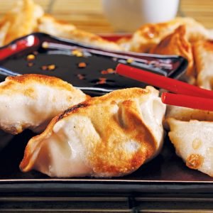 Potstickers on Black Plate with Red Chopsticks Food Picture