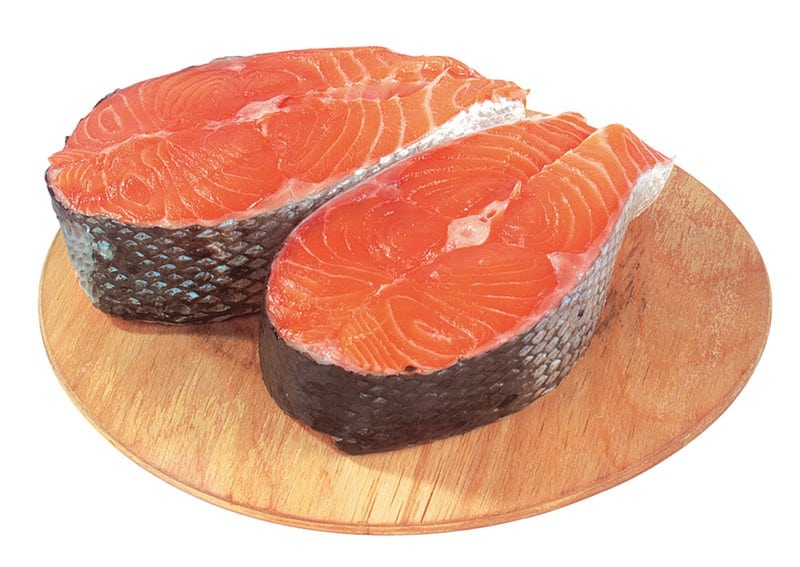 Salmon steaks on circular wooden board with white background Food Picture