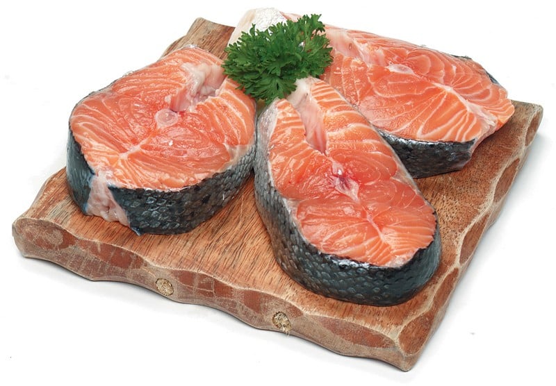 Salmon steaks with garnish on dark wooden slab with white background Food Picture