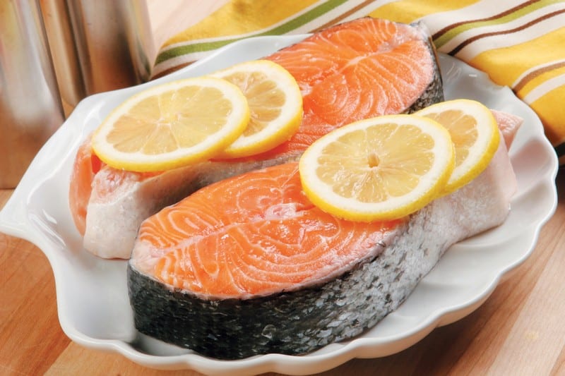 Salmon steaks with lemon on a white plate on a wooden table Food Picture
