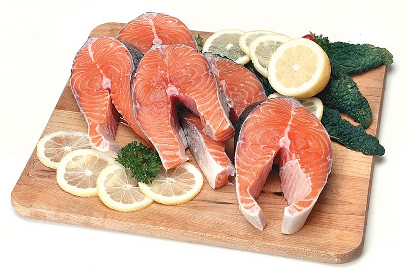 Salmon steaks on wooden slab with lemon and garnish Food Picture