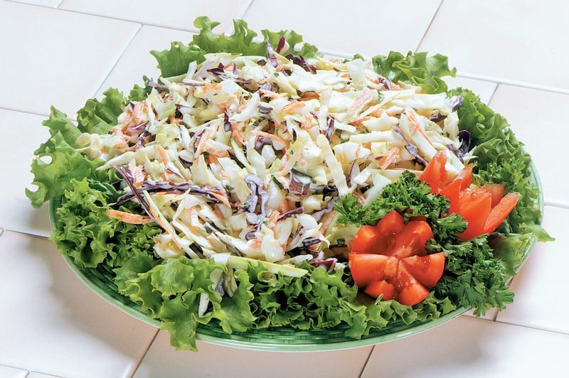 Coleslaw over Greens in Light Green Bowl on White Tile Food Picture