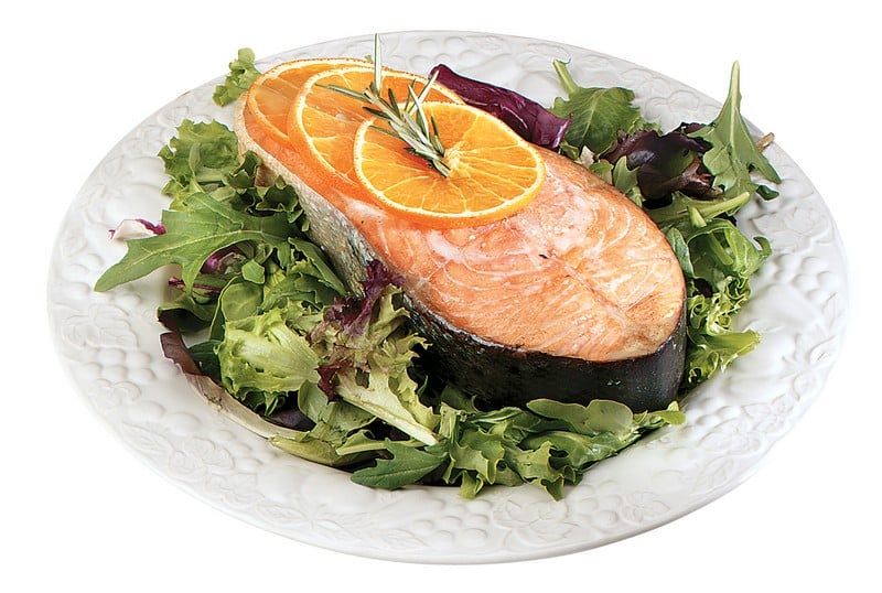 Salmon Steak over Greens with Garnish on White Plate Food Picture