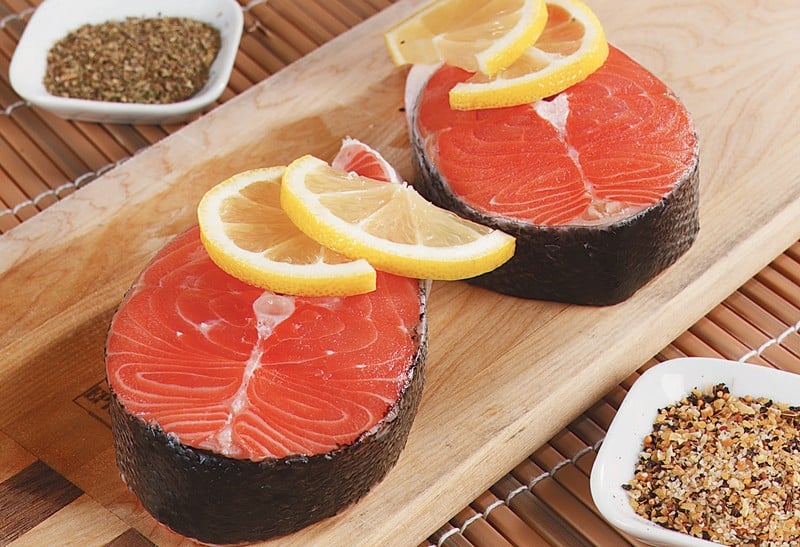 Salmon Steaks on Wooden Board Topped with Sliced Lemons Food Picture