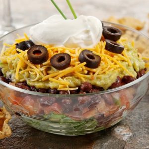 Seven Layer Salad in a bowl with Chips Food Picture