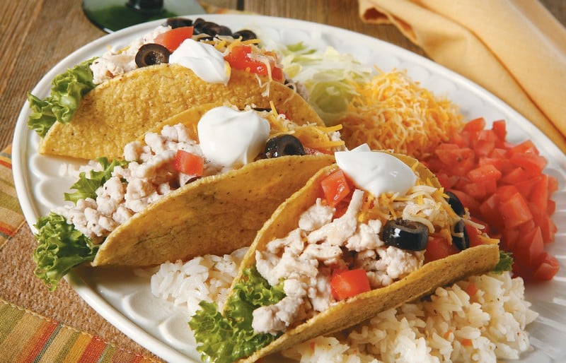 Turkey Hard Shell Tacos with Cheese and Diced Vegetables on White Platter Food Picture