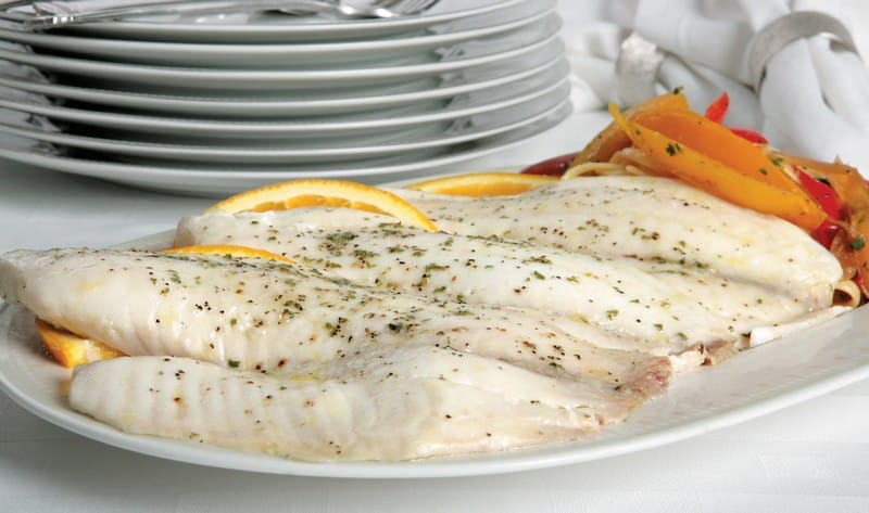 Tilapia on serving dish with garnish and plates in the background Food Picture