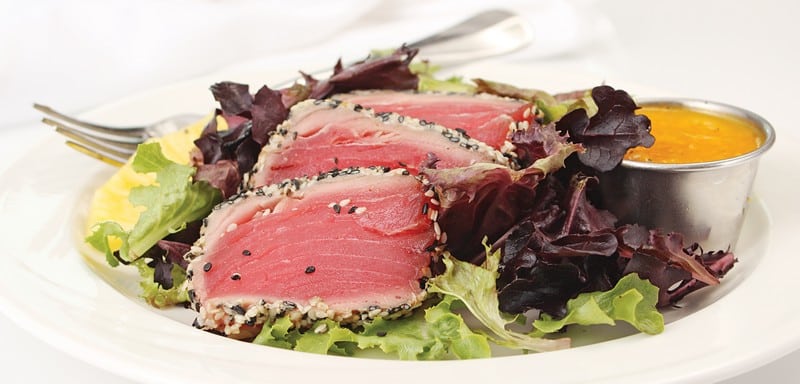 Seared tuna salad with fork and dressing on white plate Food Picture