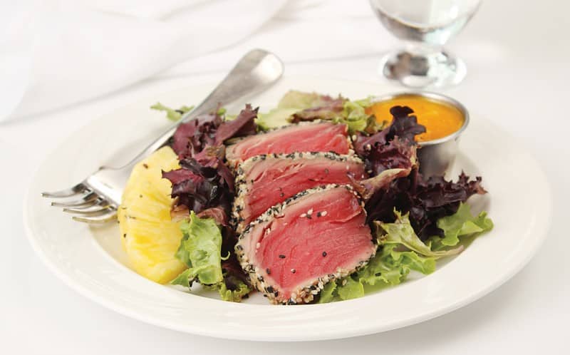 Seared tuna salad with dressing and fork on a white plate Food Picture