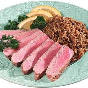 Tuna steak with rice and garnish on light colored plate Food Picture