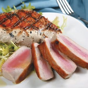 Tuna steak whole and sliced on white plate with blue napkin Food Picture