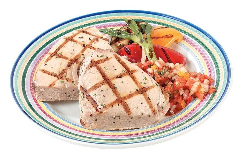 Tuna steak with garnish on multi-colored plate with white background Food Picture