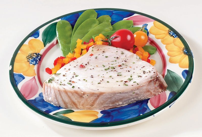 Tuna steak with seasoning and garnish on multi-colored plate Food Picture
