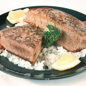 Tuna steak with rice and garnish on black plate Food Picture