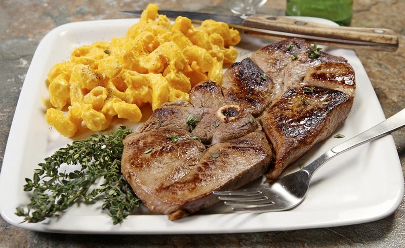 Medium-Well Venison Steak with Homemade Macaroni and Cheese on White Plate on Granite Countertop Food Picture